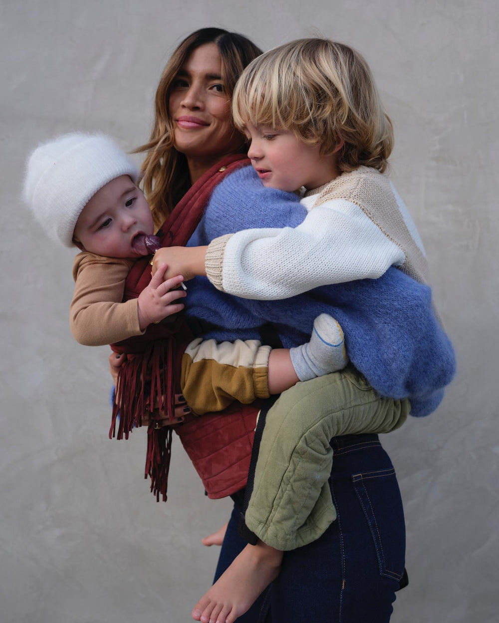 Rocky Barnes holding her children while eating lollipops