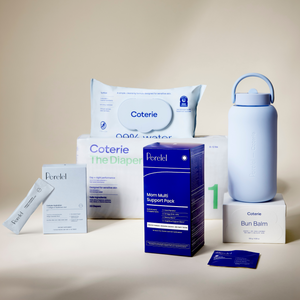 A coordinated set of Perelel and Coterie products arranged on a warm beige studio background: a large pack of wipes, a diaper box, a blue mom multi-support pack, a white bun balm box, cellular hydration box and travel stick, and a pale blue bottle.
