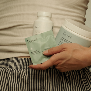 hand holding mom multi pill sachet with hydration powder tub and daily probiotic pill bottle